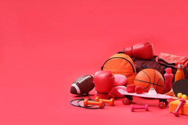 Kırmızı arkaplanda birçok farklı spor ekipmanı, metin için boşluk