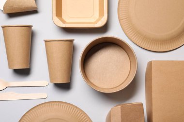 Çevre dostu gıda ambalajı. Açık gri arkaplanda kağıt kaplar ve sofra takımı, düz konum