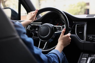Woman holding steering wheel while driving her car, closeup