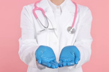 Steteskoplu doktor pembe arka planda bir şey tutuyor, yakın plan.