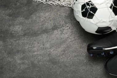 Spor malzemeleri. Futbol topu, ağ ve spor ayakkabıları gri desenli masada, düz yerde. Metin için boşluk
