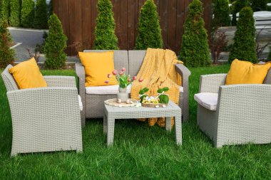 Paskalya süsleri. Vazodaki lale buketi, tavşan figürleri ve arka bahçedeki masada süslü yumurtalar.