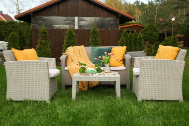 Paskalya süsleri. Vazodaki lale buketi, tavşan figürleri ve arka bahçedeki masada süslü yumurtalar.