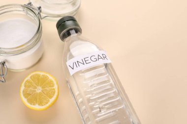 Çevre dostu doğal temizleyiciler. Şişede sirke, bej arka planda limon ve bir kavanoz soda. Metin için boşluk