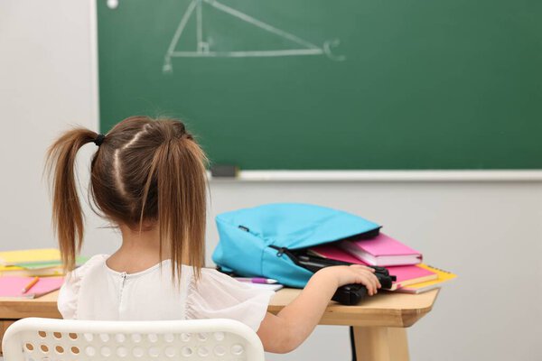 Child taking gun out of backpack at desk in classroom. School shooting