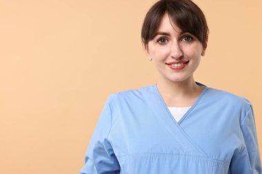 Portrait of smiling medical assistant on beige background. Space for text