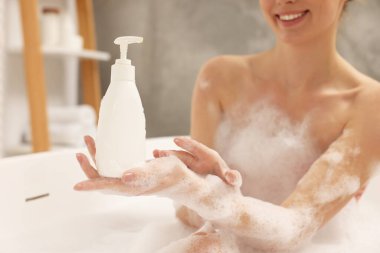 Woman taking bath with shower gel in bathroom, closeup
