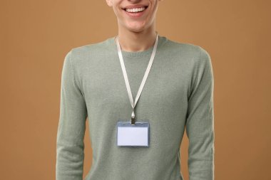 Açık kahverengi arka planda boş rozetli adam, yakın plan.