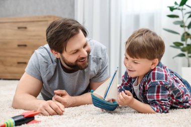Happy dad and son playing toys together at home