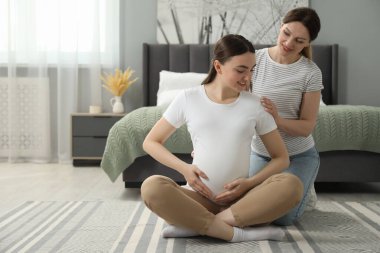 Doula hamile kadına yatak odasında masaj yapıyor. Çocuk doğumu hazırlığı