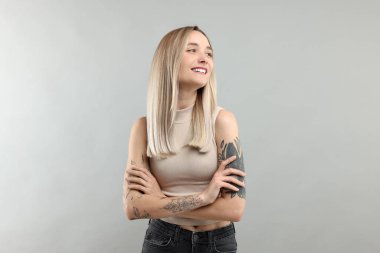 Portrait of beautiful tattooed woman on gray background