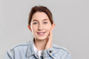 Gri arka planda diş telleri olan gülümseyen kadın portresi