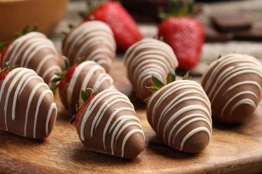 Delicious chocolate covered strawberries on wooden board, closeup
