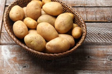 Tahta masada hasır sepette çiğ patates.