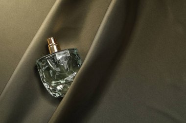 Parfüm şişede koyu ipek kumaş, üst görünüm.