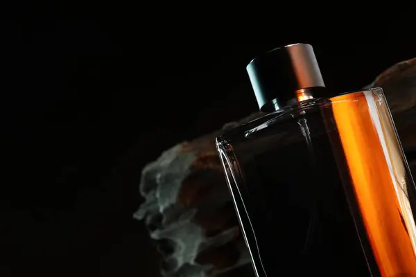 Luxury men`s perfume in bottle against dark background, space for text