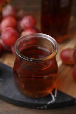 Cam kavanozda şarap sirkesi ve masada üzüm, yakın plan.