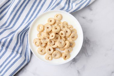 Kahvaltı gevreği. Lezzetli mısır halkaları, beyaz mermer masada süt kasesi, üst manzara.