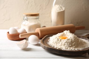 Para kazanmak. Sarısı olan un yığını, yuvarlanan iğne ve yumurtalar beyaz ahşap masada, yakın plan.