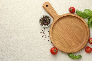 Cutting board, basil, spices and tomatoes on white textured table, flat lay. Space for text