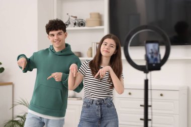 Smiling teenage bloggers dancing while streaming at home