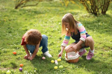 Easter celebration. Cute little children hunting eggs outdoors