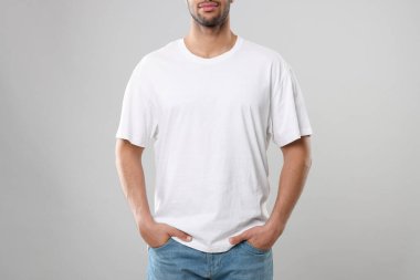 Man wearing white t-shirt on gray background, closeup