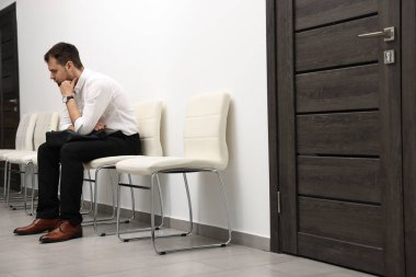 Man with briefcase waiting for job interview indoors