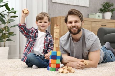 Family portrait of happy dad and son near tower of cubes at home