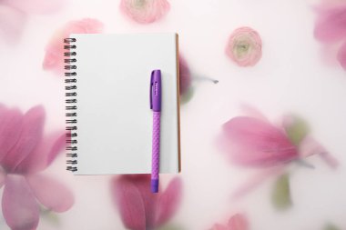 Konuk listesi. Bahar çiçekli arka planda defter ve kalem düz yatıyordu. Metin için boşluk