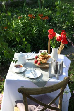 Güzel bir buket lale ve taze pişmiş waffle bahçede çay içmek için servis edilen masada.