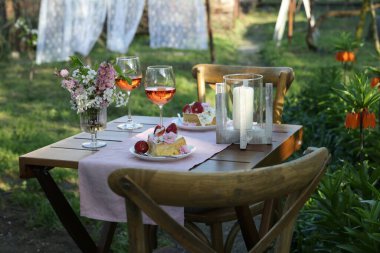 Baharda çiçekli vazo, şarap ve pasta bahçede romantik bir randevuya servis edilir.
