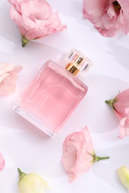 Parfüm ve çiçek dekoru beyaz arka planda, düz yerde.
