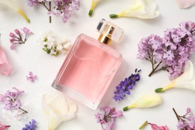 Parfüm ve çiçek dekoru beyaz arka planda, düz yerde.