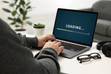 Loading screen displaying progress. Man working on laptop at table indoors, closeup