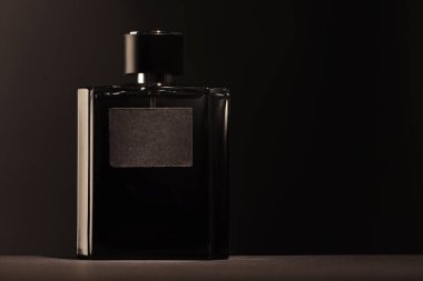 Luxury men`s perfume in bottle on table against dark background, space for text