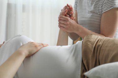 Doula evde hamile bir kadına bakıyor, yakın plan. Çocuk doğumu hazırlığı
