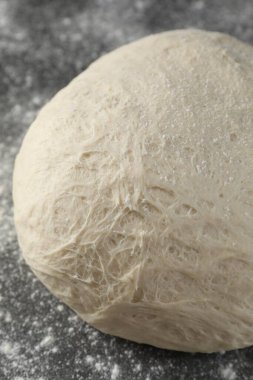 Raw homemade dough and flour on black table, above view