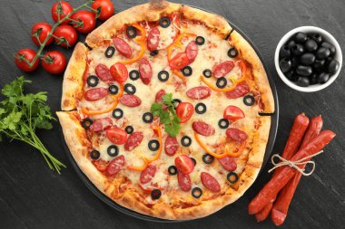 Tasty pizza with dry smoked sausages, olives, tomatoes, pepper and parsley on grey table, top view