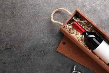 Ahşap kutuda bir şişe şarap ve siyah desenli masada tirbuşon. Metin için boşluk