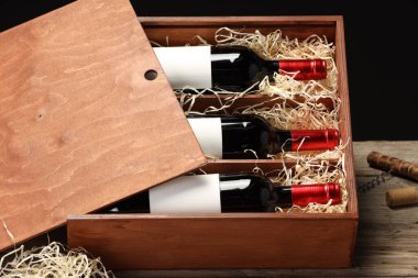 Ahşap masanın üzerinde şarap şişeleri olan bir kutu.