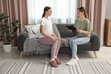 Doula evdeki kanepede hamile bir kadınla çalışıyor. Çocuk doğumu hazırlığı