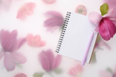 Konuk listesi. Not defteri, kalem ve manolya bahar çiçekli arka plan, düz yatış. Metin için boşluk