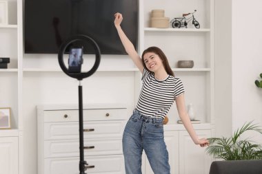 Smiling teenage blogger dancing while streaming at home