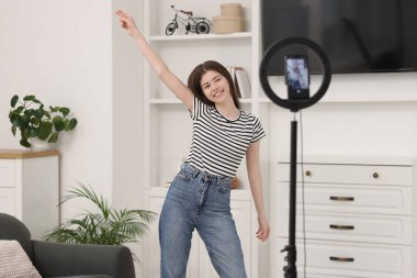 Smiling teenage blogger dancing while streaming at home