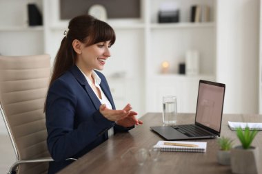 Ofisteki ahşap masada görüntülü konuşma yapan kadın.