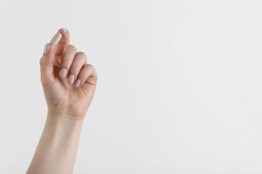 Beyaz arka planda vitamin hapı tutan kadın, mesaj için yeri olan yakın plan. Sağlık takviyesi
