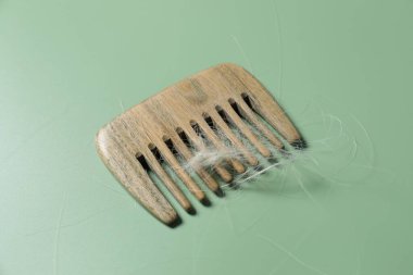 Yeşil arka planda saçı dökülmüş tarak