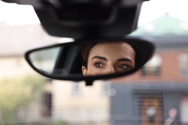 Woman driving her car, reflection in rear view mirror