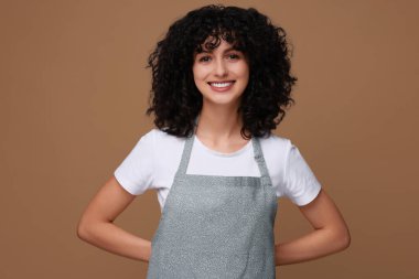 Kahverengi arka planda mutfak önlüğü giyen mutlu kadın. Tasarım için model